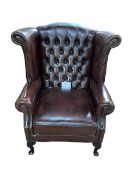 Thomas Lloyd brown buttoned leather and studded wing armchair.