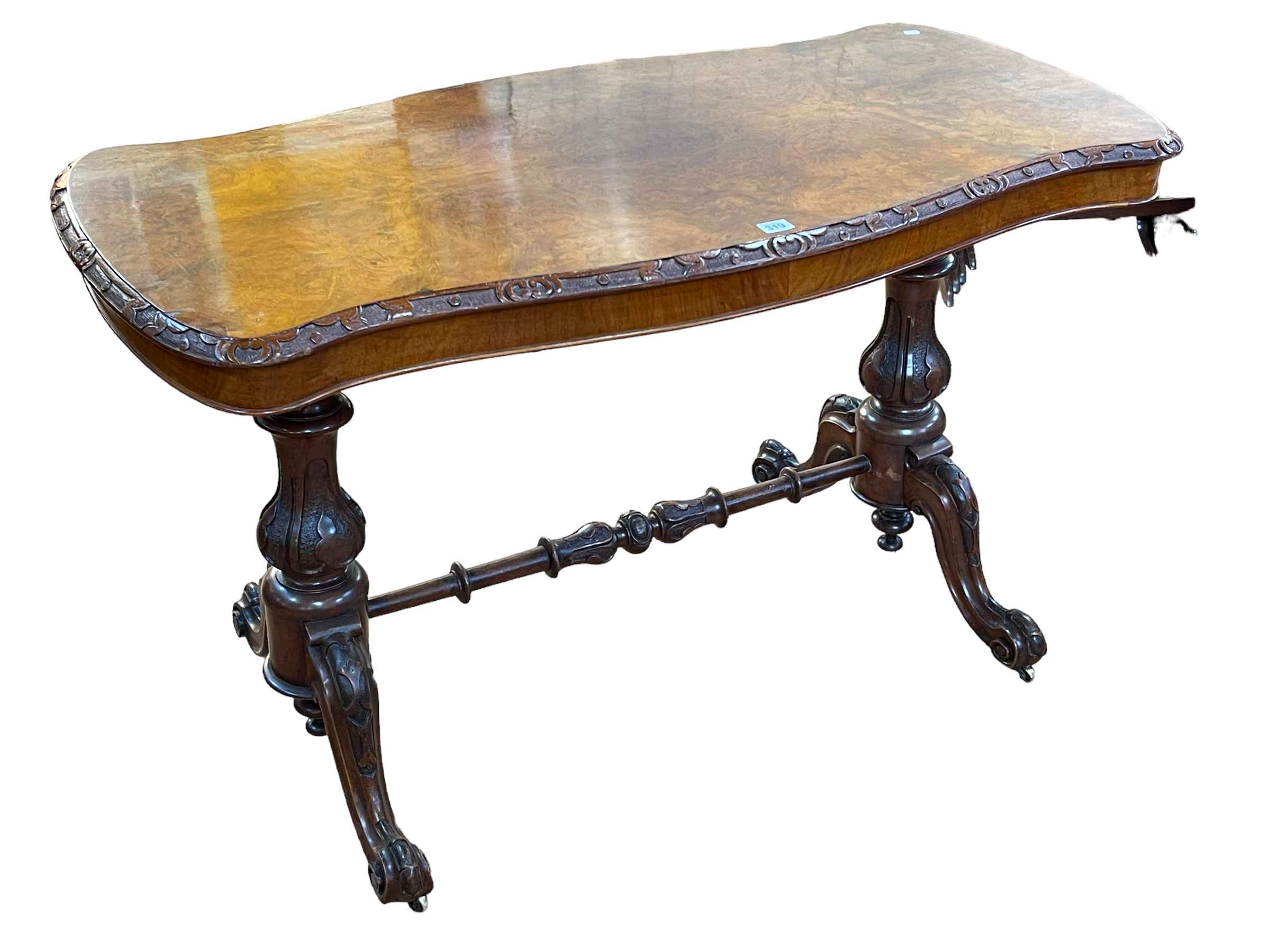 Victorian walnut centre table of serpentine form raised on two carved pedestals joined by turned