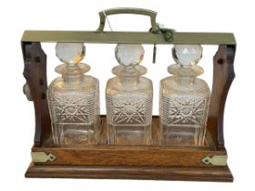 Oak and brass bound three bottle tantalus with key.