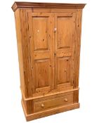 PIne wardrobe having two panelled doors above a base drawer, 190cm by 111cm by 59cm.