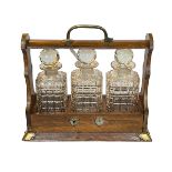 Oak and brass bound three bottle tantalus with key, 33cm.