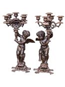 Pair of cast metal cherub candlesticks, 65cm.