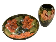 Moorcroft pottery bowl and vase, both decorated with hibiscus on green ground.