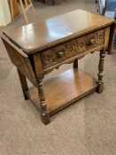 Carved oak drop leaf side table having frieze drawer raised on turned legs joined by undershelf,