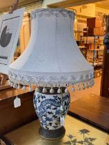 Chinese blue and white pottery table lamp decorated with dragon and floral scene with silk shade.