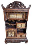 Ornately carved Oriental cabinet having applied decorated panel doors and drawers and open