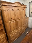 Pine combination wardrobe having two doors above five drawers, 214cm by 157.5cm by 60.