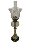 Brass column oil lamp with clear glass reservoir and etched shade.