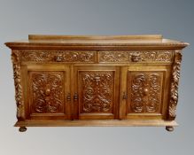 An Edwardian heavily carved oak Renaissance style triple door sideboard,