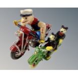 Two cast iron figures on motorbikes, Mickey Mouse and Popeye.