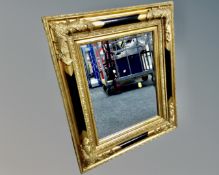 A contemporary bevel edged mirror in black and gilt cushion frame.