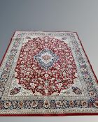 A machine made carpet of Keshan design, on red ground, 339 cm x 239 cm.
