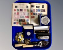 A tray containing mouth organs, plated servers, AA badge, commemorative coin,