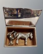 A silver plated cigarette box containing three white metal animal figures