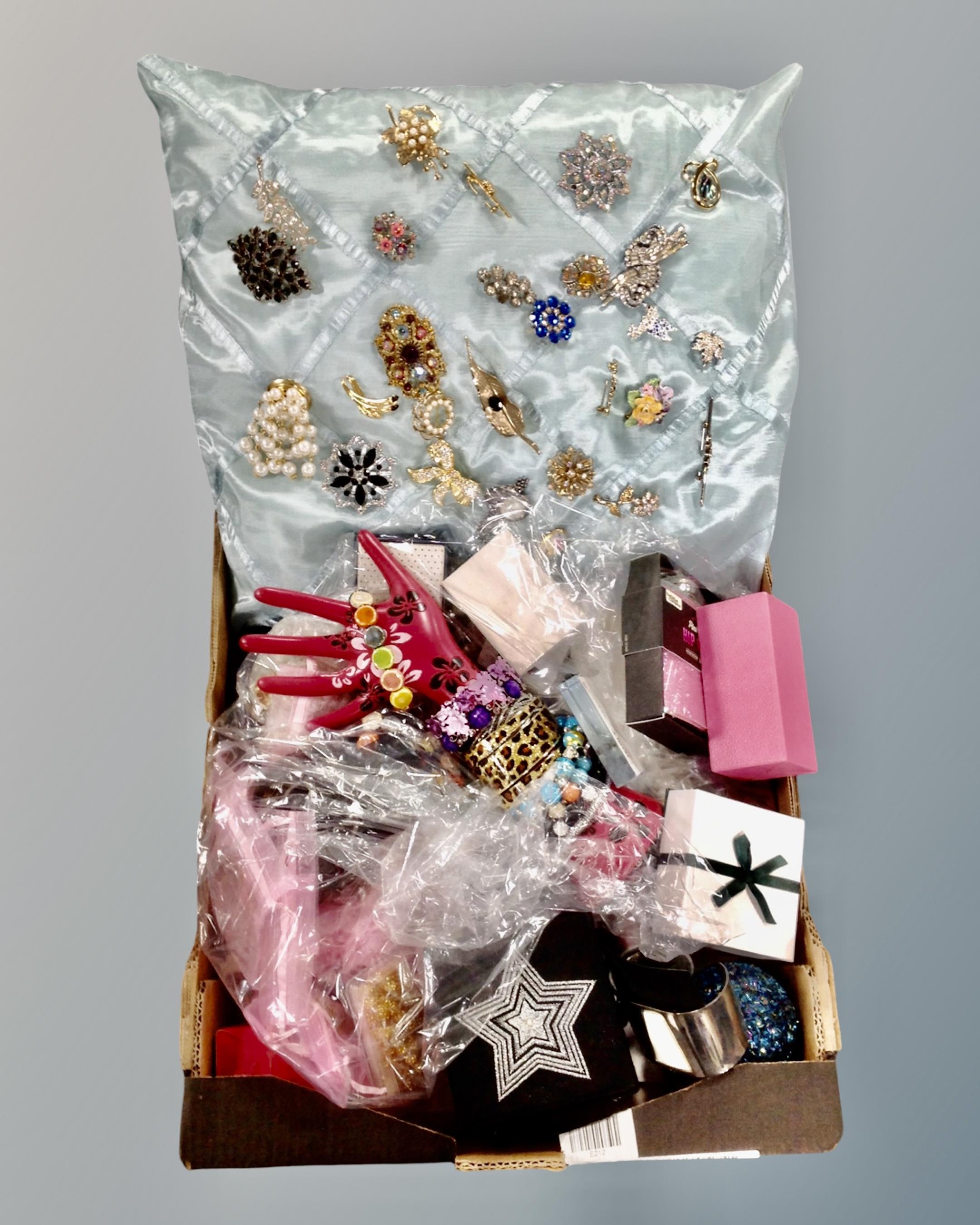 A box containing a collection of ornate brooches mounted on a cushion, costume jewellery,