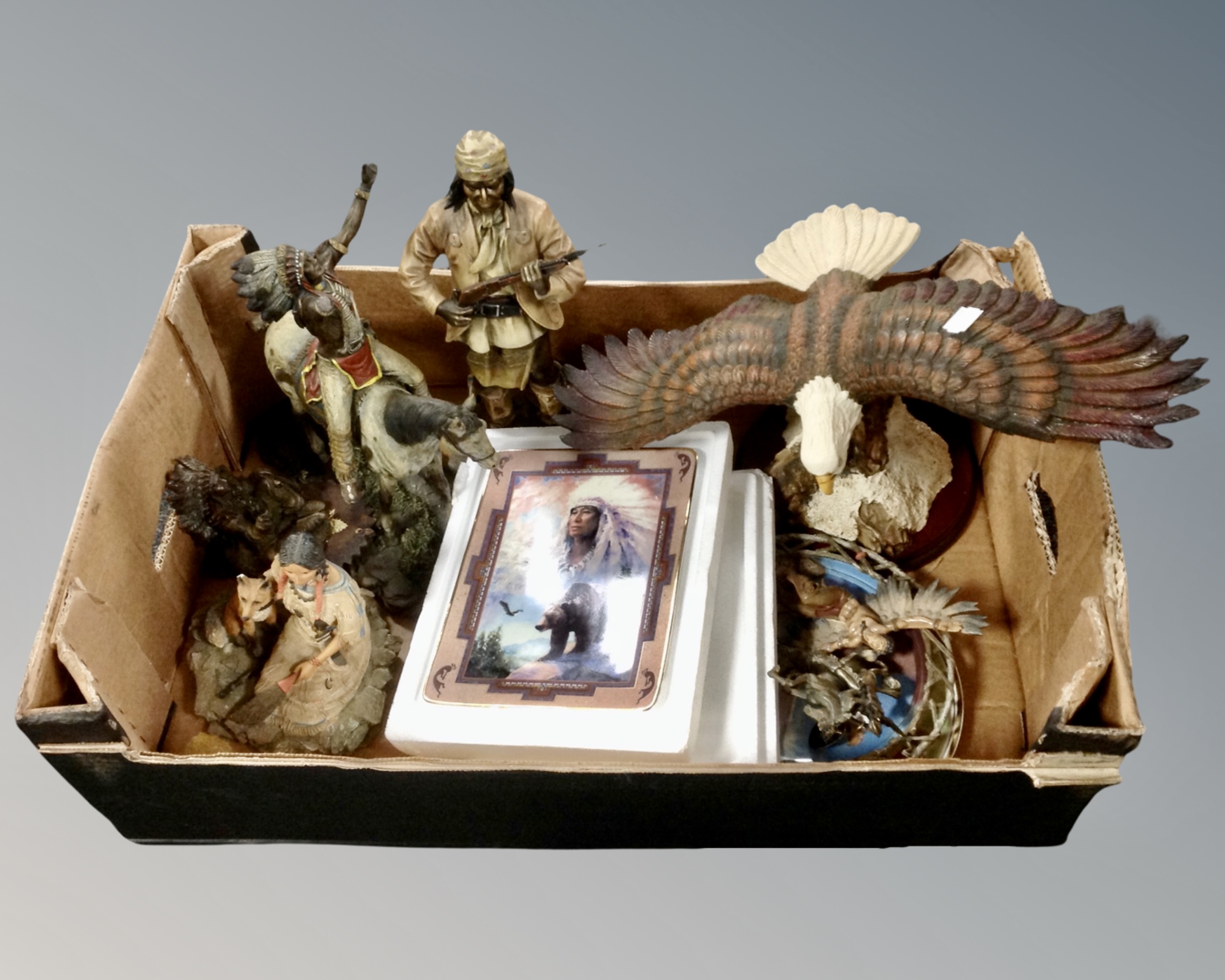 A box containing Native American figurines and wall plates.