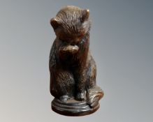 A bronze figure of a seated cat licking its paw,