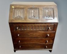 A Jaycee oak linen fold writing bureau fitted with three drawers beneath (width 75cm)