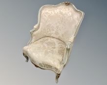 A cream and gilt French Louis XV style armchair upholstered in a cream fabric.