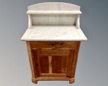 An antique pine marble topped wash stand fitted with cupboard and drawer beneath.