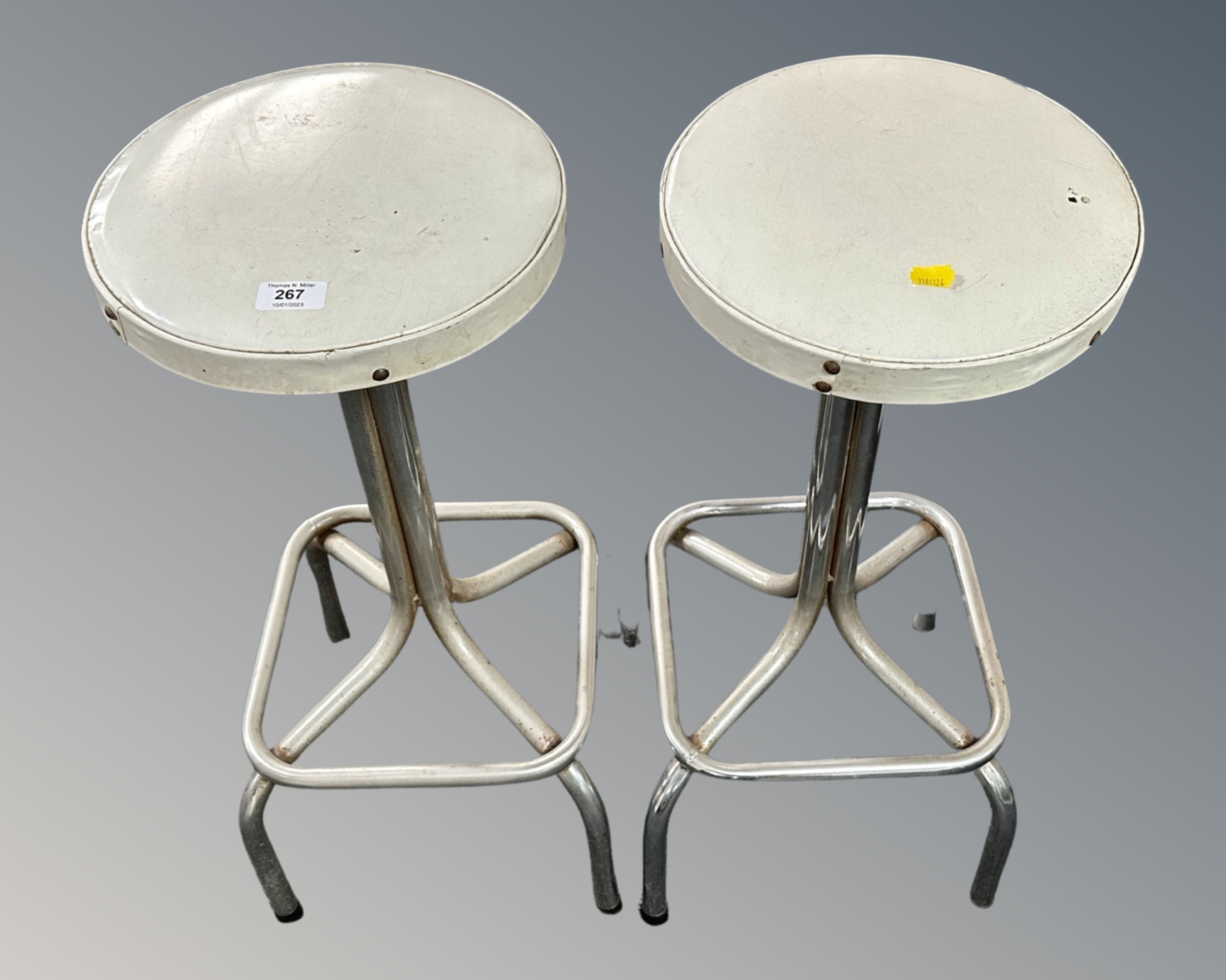 A pair of 1970s chrome tubular metal bar stools with white vinyl seats.
