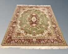 A machine made Persian design fringed carpet on green ground, 236cm by 170cm.