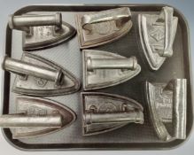 A tray containing eight antique flat irons.
