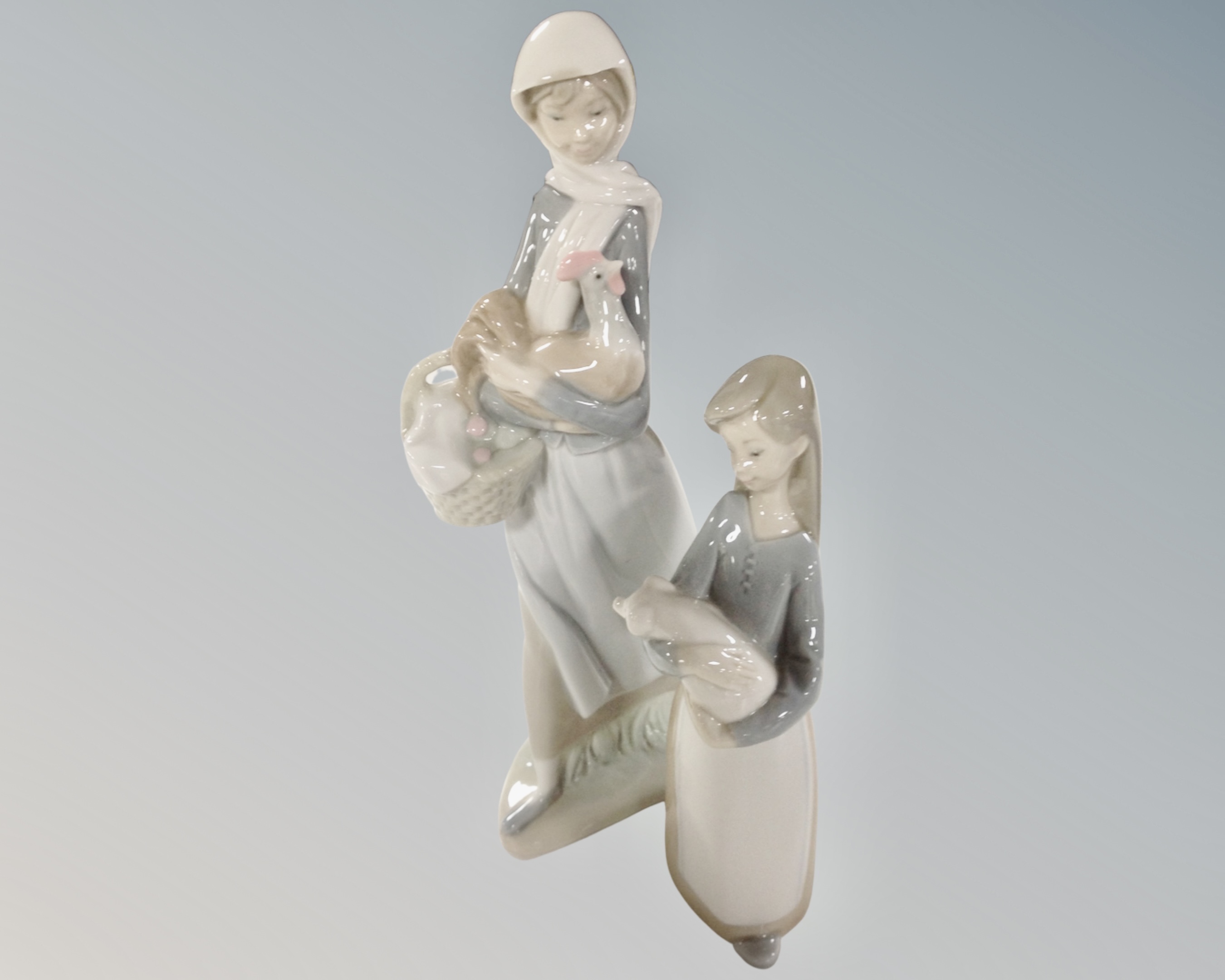 Two Lladro figures, girl with chicken and girl with pig.