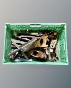 A crate containing a quantity of vintage woodworking planes, block planes and hand saws.
