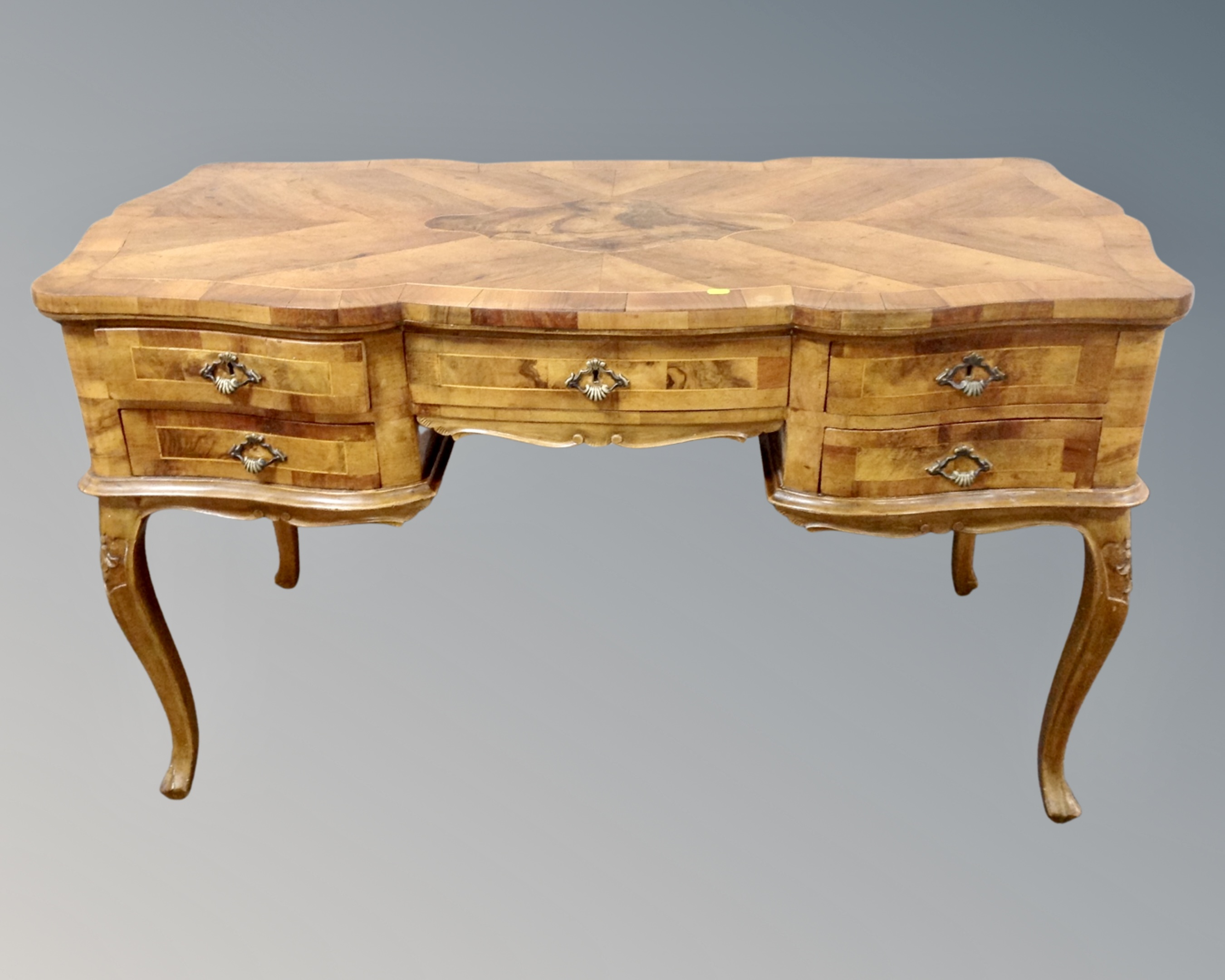 An early 20th century Italian walnut parquetry writing desk on cabriole legs fitted with five