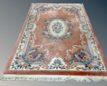 A Chinese floral embossed fringed carpet on pink ground, 295cm by 185cm.