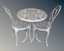 A circular cast metal patio table together with two chairs.