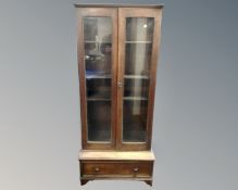 An Edwardian oak double door glazed bookcase fitted with a drawer beneath (width 71cm)