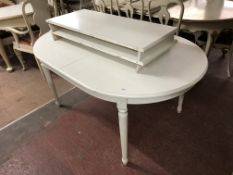 A contemporary white oval extending dining table with two leaves,