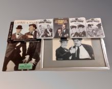 A box containing Laurel and Hardy memorabilia including framed picture, poster book, DVDs.