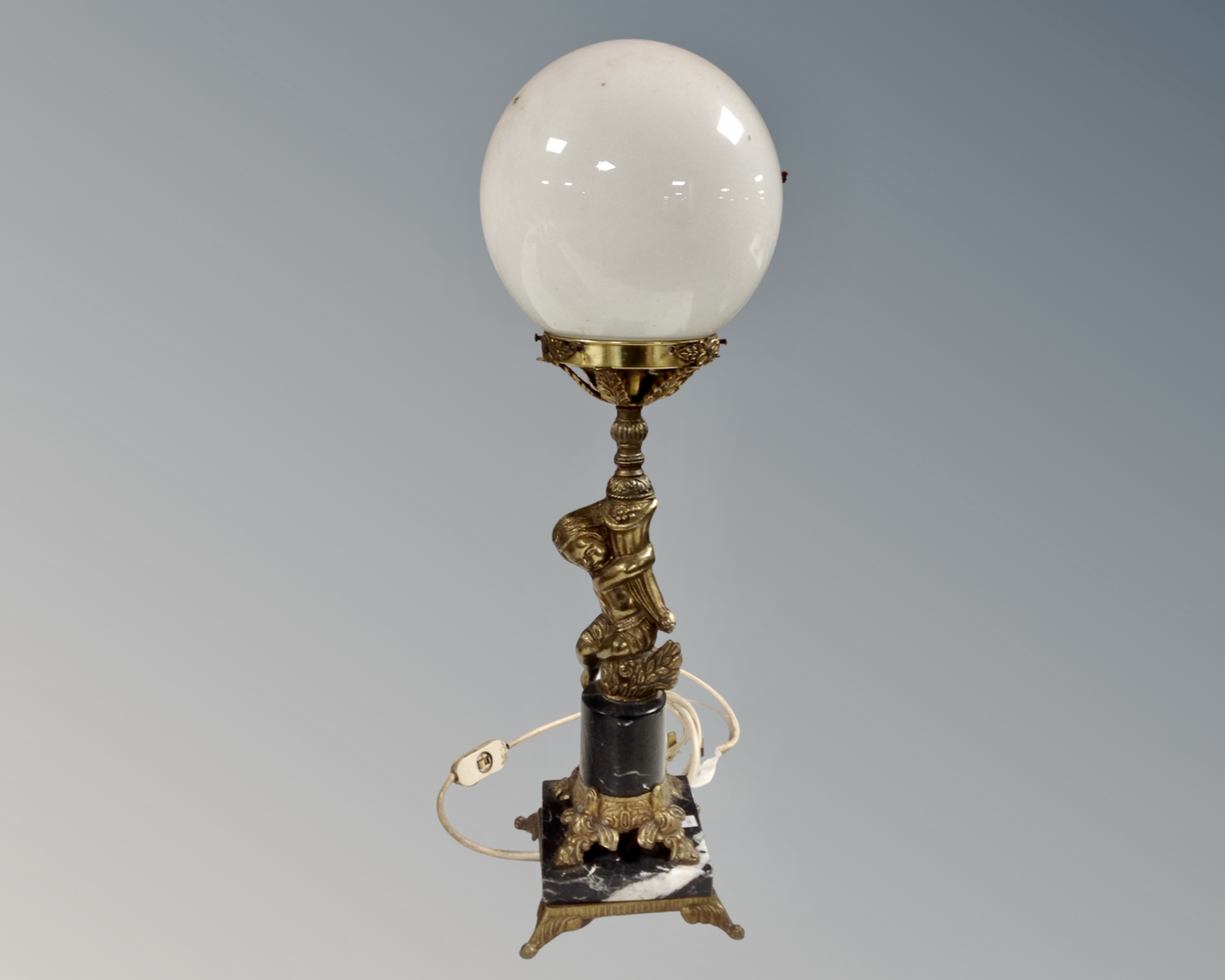 A gilt metal and black marble figural table lamp with opaque ball glass shade (base as found)