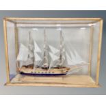 A model of a three masted sailing ship in glazed pine display case, 97cm by 67cm by 33cm.