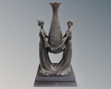 A cast bronze figure of two women holding vase aloft, on black marble stepped base.
