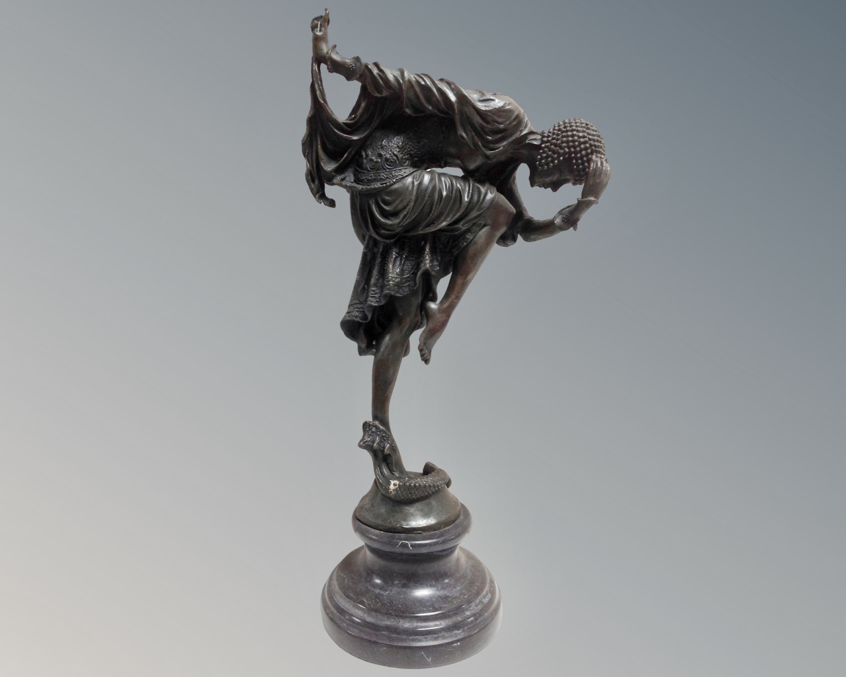 An Art Deco style cast bronze figure of a woman in flapper dress, with a serpent at her feet.