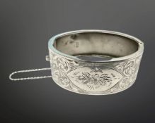 An engraved silver hinged bangle with safety chain, 65mm by 53mm.