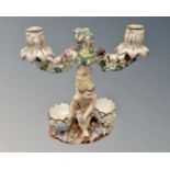 A pair of continental porcelain twin branch candelabrum decorated with putti (a/f)