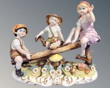 A continental porcelain figure group of children on a see-saw.
