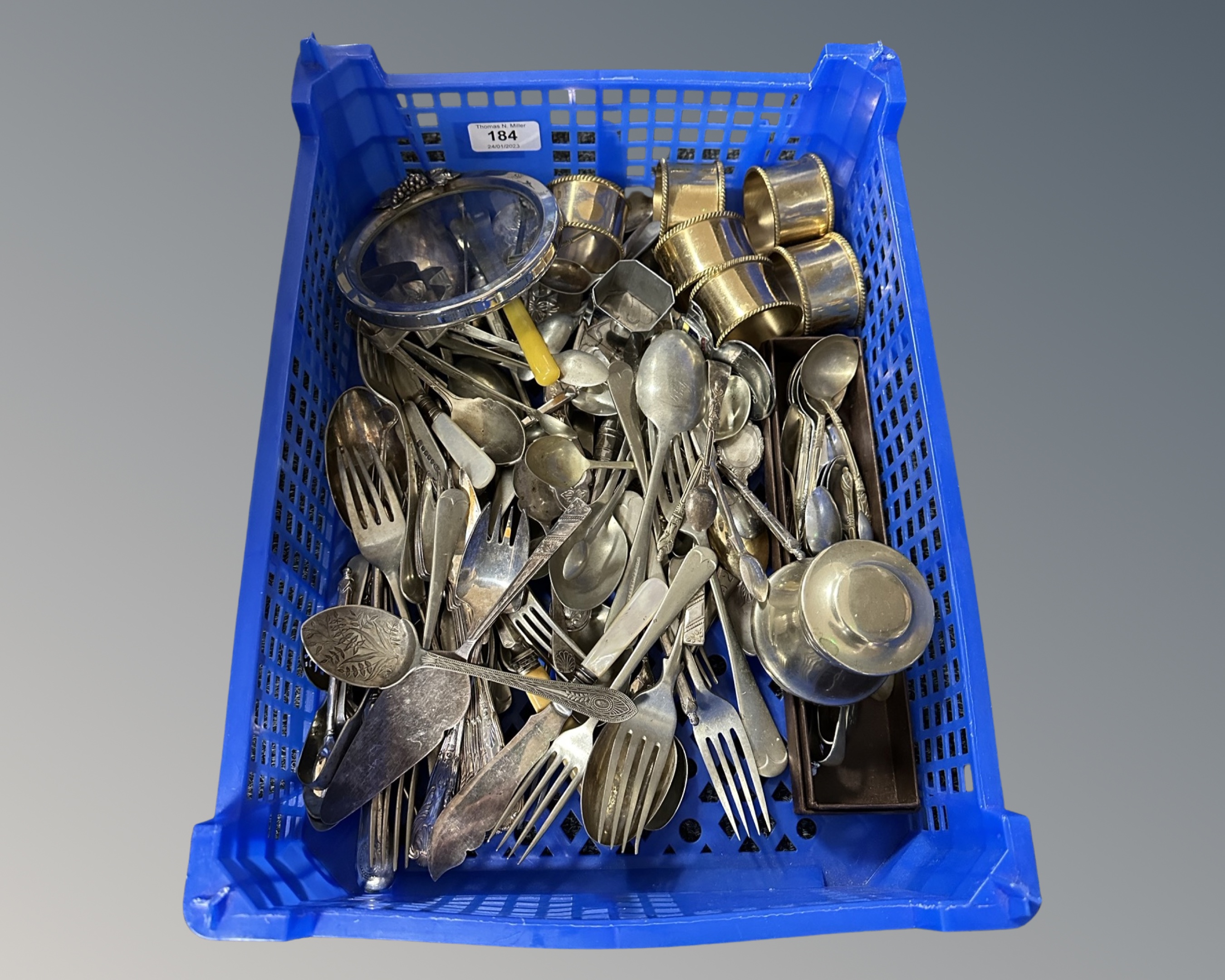 A crate containing assorted loose stainless steel and EPNS cutlery, napkin rings etc.