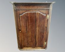 A George III oak panel door hanging corner cabinet.