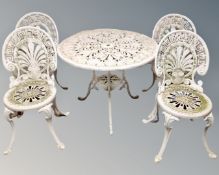 A circular cast metal patio table together with four chairs.