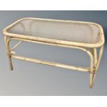 A 20th century bamboo and wicker two tier coffee table with glass shelves.