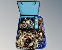 A tray containing a tin and jewellery box containing a large quantity of assorted costume jewellery.