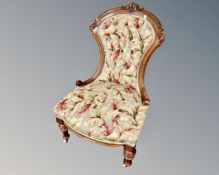 A Victorian carved walnut framed nursing chair upholstered in a floral button back fabric.