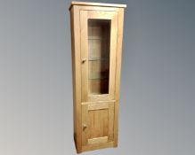 A contemporary oak narrow glazed door display cabinet fitted with cupboard beneath.