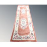 A Chinese embossed carpet runner on peach ground.